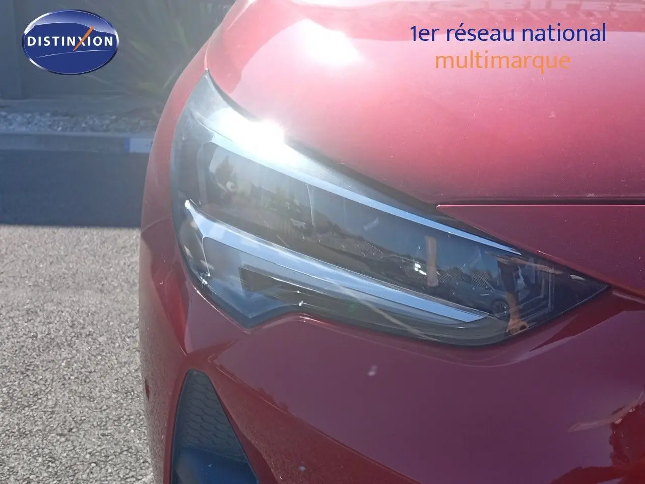 Gros plan sur le phare avant gauche d'une Opel Corsa rouge Kardio métal avec toit noir, modèle 2023.