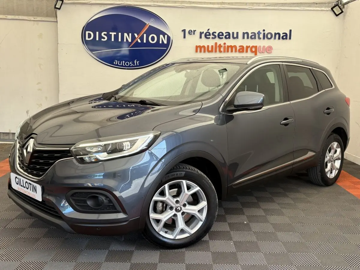 Renault Kadjar Intens gris foncé vu en 3/4 avant droit dans un showroom avec logo Distinxion en arrière-plan.