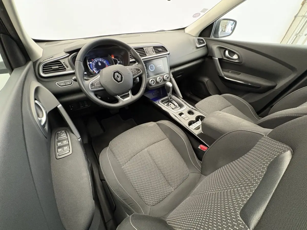 Intérieur avant Renault Kadjar gris, vue côté conducteur, tableau de bord avec écran tactile et volant multifonctions.