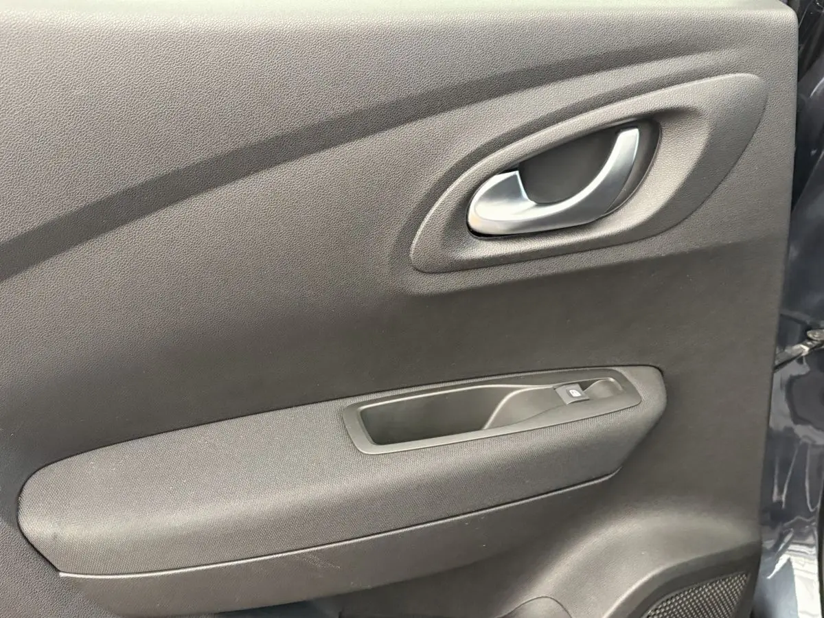 Gros plan sur la porte intérieure côté gauche du Renault Kadjar gris foncé, avec poignée argentée et commande de vitre.