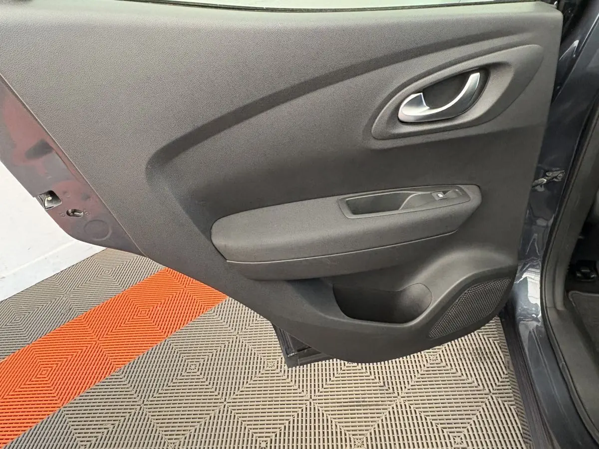 Porte arrière gauche ouverte du Renault Kadjar gris foncé, montrant la garniture intérieure noire avec poignée et commande de vitre.