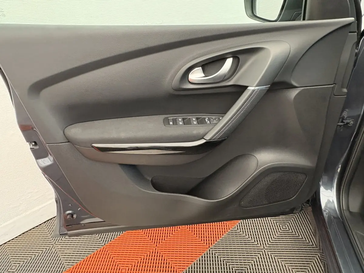 Vue intérieure côté gauche de la porte avant gris foncé du Renault Kadjar avec commandes de vitres et poignée argentée.