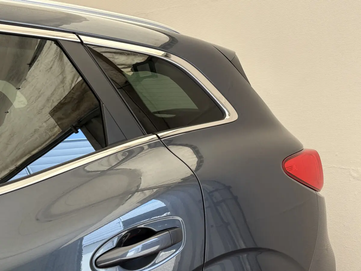 Vue latérale arrière côté droit du Renault Kadjar gris foncé, mettant en valeur la poignée de porte et le feu arrière.