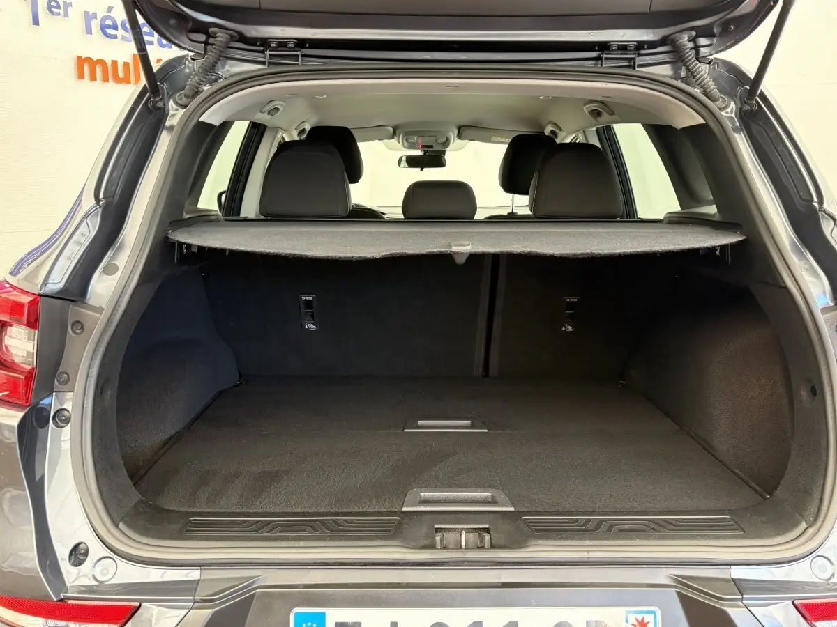 Coffre ouvert d’un Renault Kadjar Intens gris foncé, vue arrière montrant l’espace de chargement et la tablette cache-bagages.