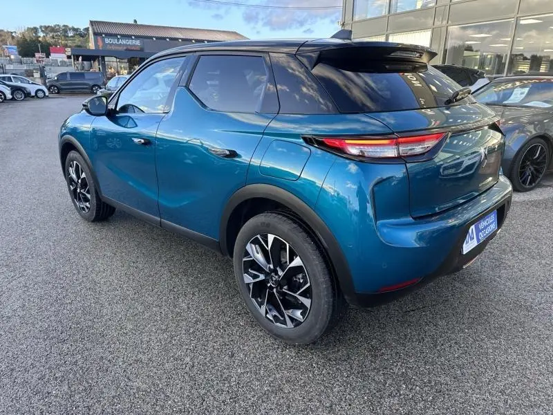 Vue 3/4 arrière droite d'une DS3 bleu métallisé avec toit noir et jantes alliage distinctives.