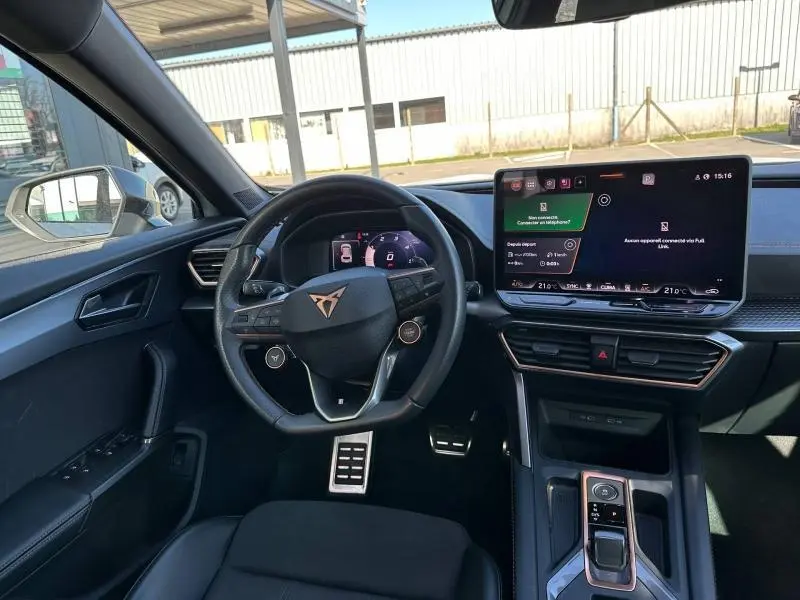Vue intérieure côté conducteur du CUPRA Formentor blanc Nevada, mettant en valeur le volant multifonction et l'écran tactile central.
