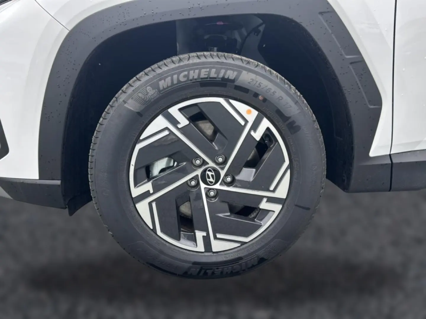 Gros plan sur la roue avant gauche blanche du Hyundai Tucson 2026 avec jante alliage noire et argentée Michelin.