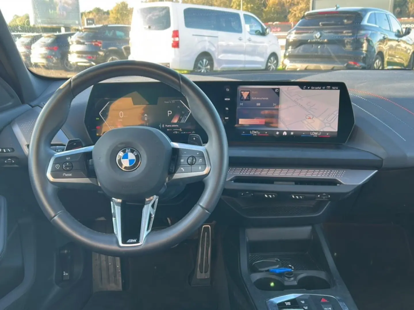 Vue intérieure du poste de conduite de la BMW Série 1 2025, avec volant sport et écran tactile central.