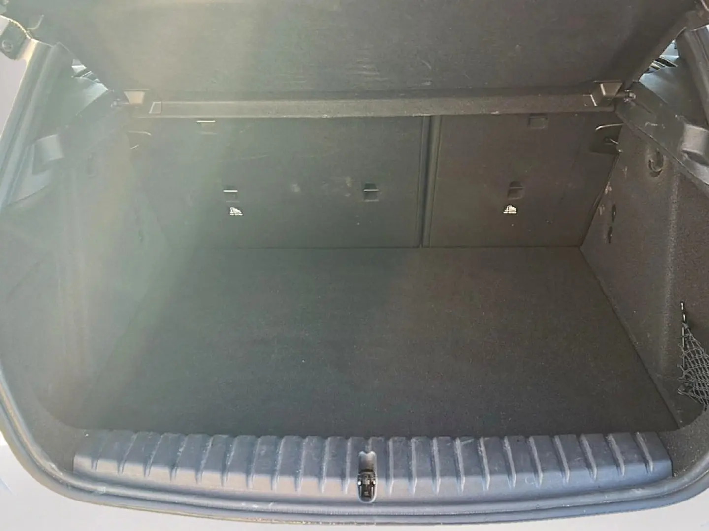 Coffre ouvert vu de l'arrière d'une BMW Série 1 blanche, montrant un espace de chargement vide et propre.