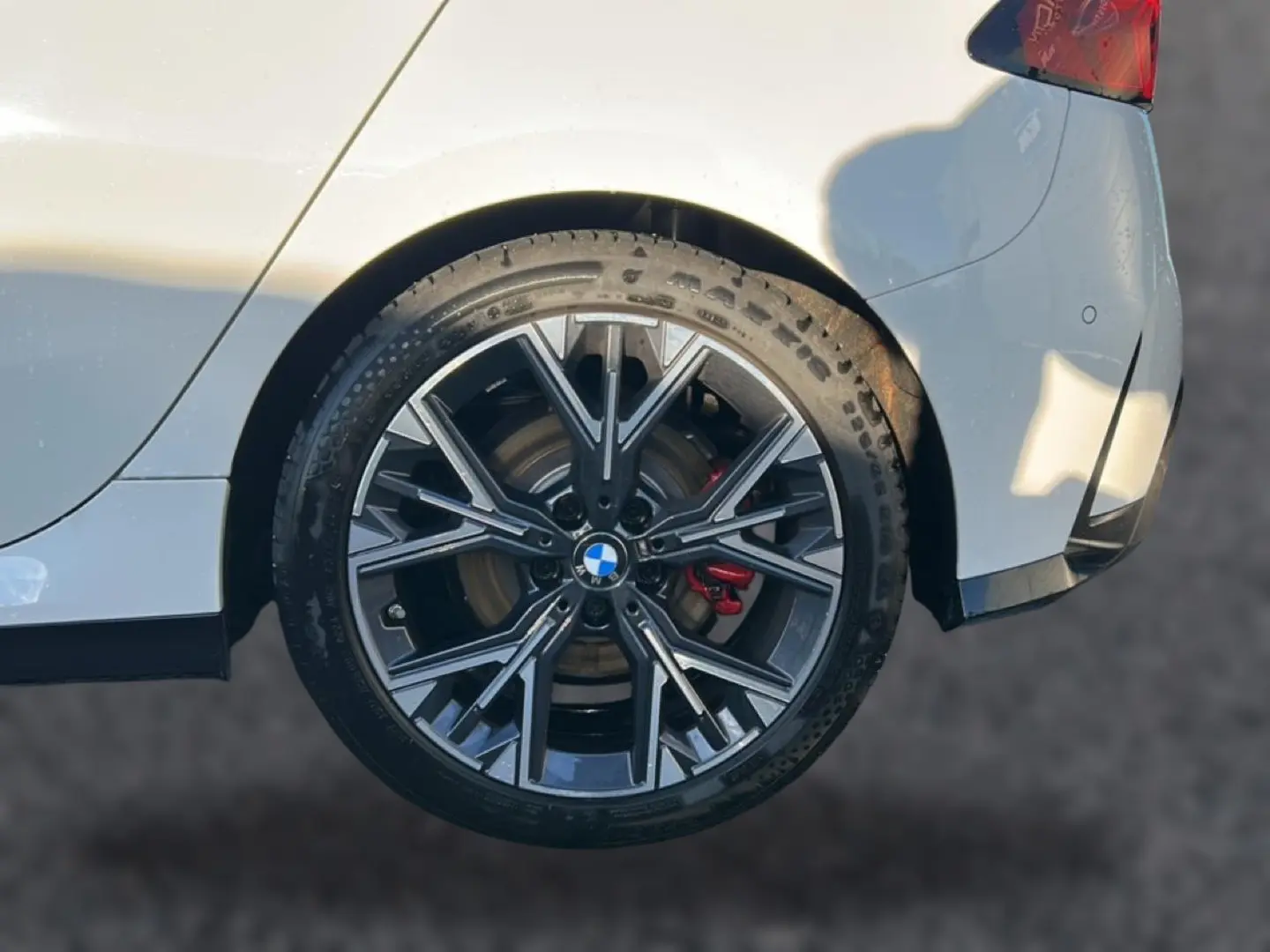 Gros plan sur la jante arrière droite bicolore en Y de la BMW Série 1 blanche alpine avec étrier de frein rouge visible.