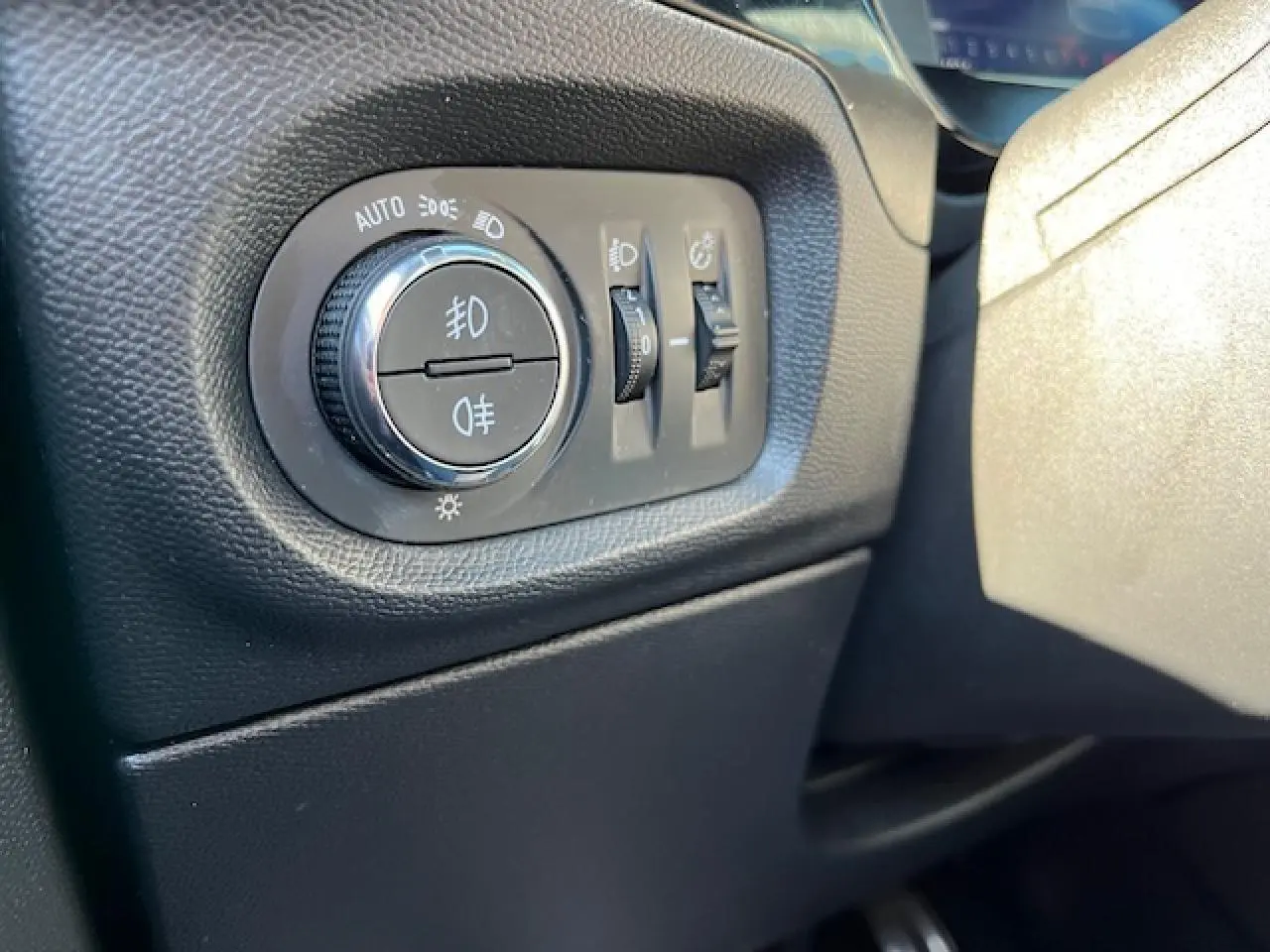 Gros plan sur les commandes d'éclairage intérieures noires de l'Opel Corsa 1.2i Turbo gris et noir, côté gauche du tableau de bord.
