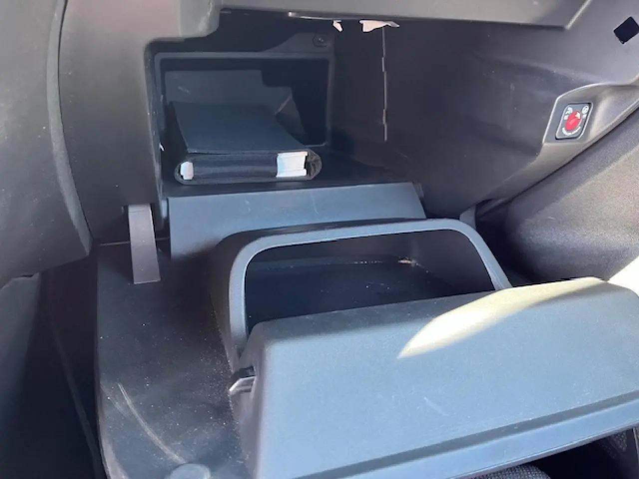 Intérieur de la boîte à gants ouverte de l’Opel Corsa gris/noir, montrant un rangement avec manuel et bouton de sécurité.