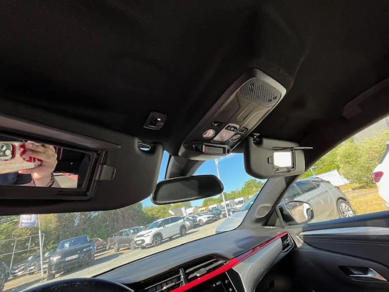 Intérieur de l'Opel Corsa 2021 gris/noir, vue du tableau de bord côté passager avec pare-soleil ouvert et rétroviseur central.