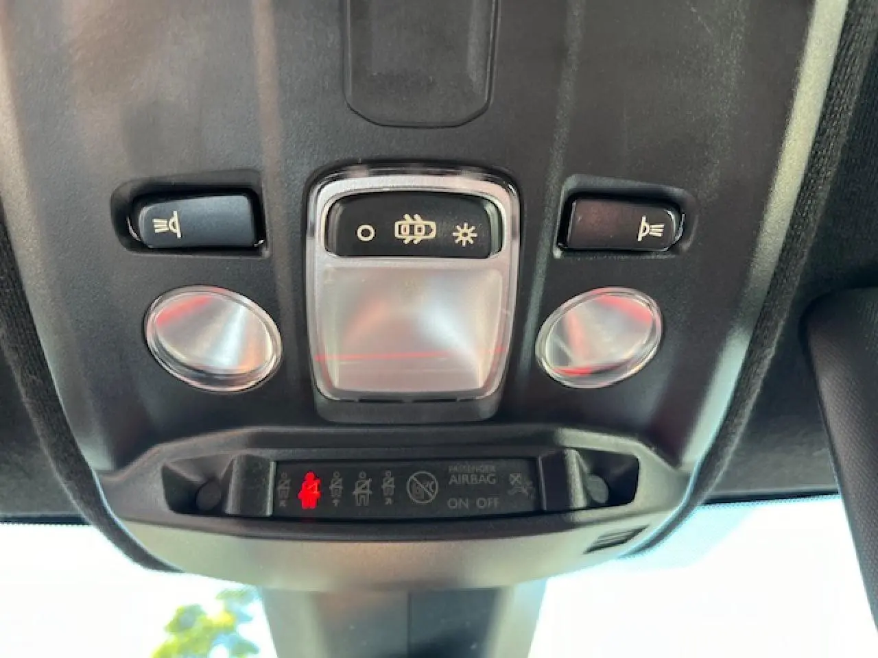 Vue en gros plan du plafonnier intérieur de l'Opel Corsa gris/noir, montrant les commandes d'éclairage et l'indicateur d'airbag passager.