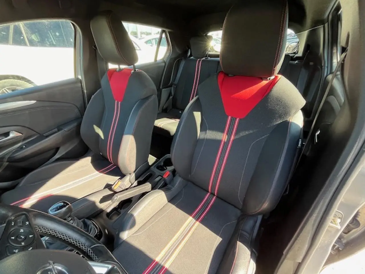 Vue intérieure avant droite de l'Opel Corsa 1.2i Turbo 2021 avec sièges sport noirs et rouges et volant cuir multifonction.
