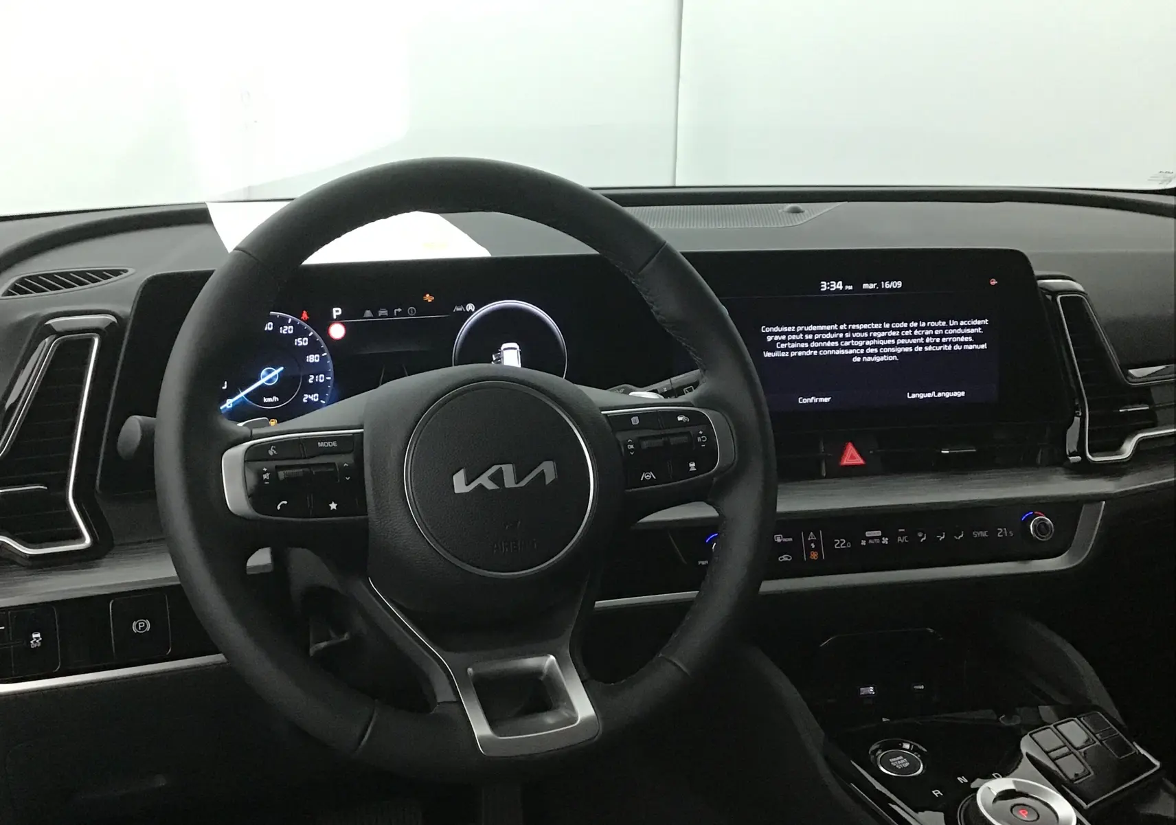 Vue intérieure du tableau de bord du Kia Sportage 2025 gris Sirius, avec volant cuir et écran digital 12,3 pouces.