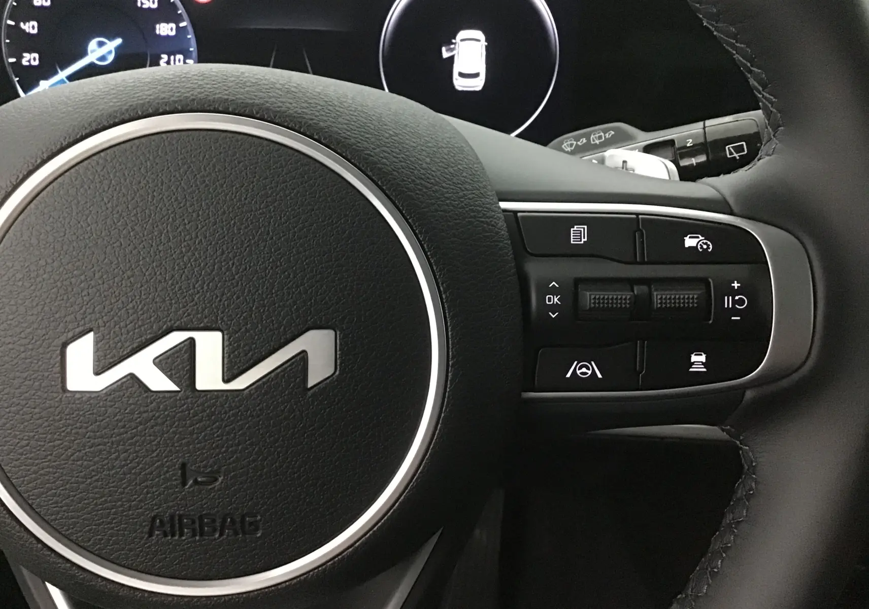Gros plan sur le volant cuir noir du Kia Sportage 2025 avec commandes multifonctions et tableau de bord digital.