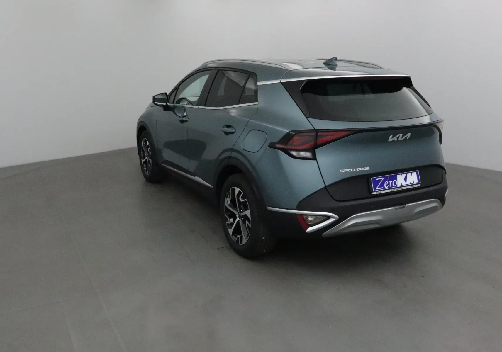 Vue 3/4 arrière gauche du KIA SPORTAGE gris Sirius 2025 avec feux LED et jantes alliage noires.