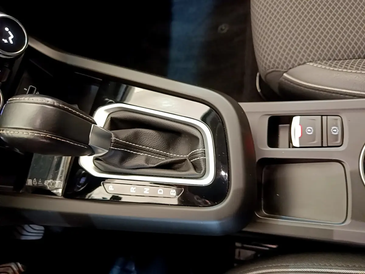 Gros plan sur la console centrale de la Renault Arkana Techno E-Tech 2023, avec levier de boîte auto cuir noir et boutons frein électrique.