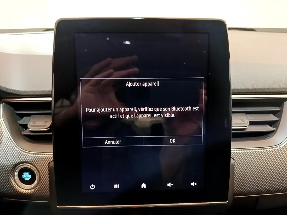 Écran tactile central allumé avec message Bluetooth dans l’habitacle du Renault Arkana bleu, vue de face rapprochée.