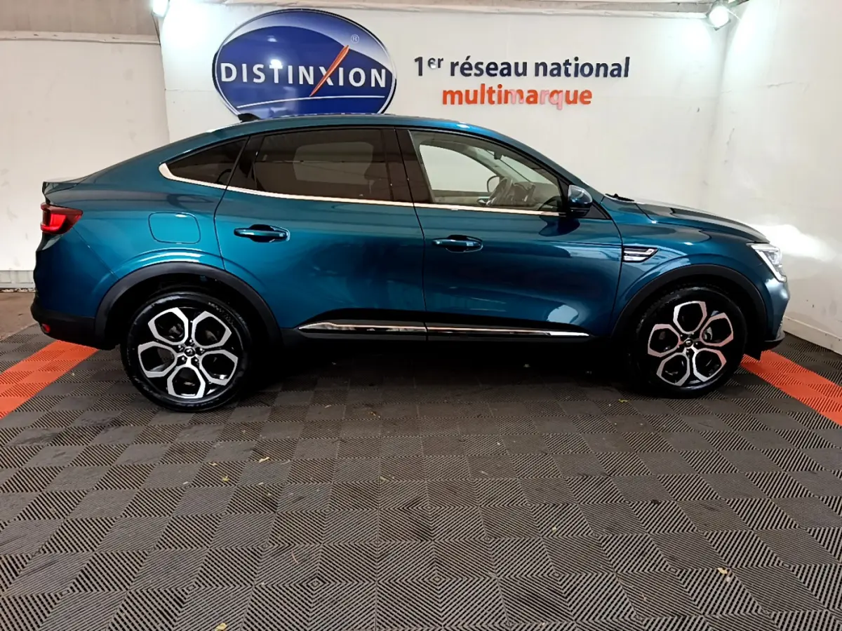 Profil droit d'un Renault Arkana bleu 2023, soulignant ses jantes alliage distinctives et sa silhouette coupé SUV.