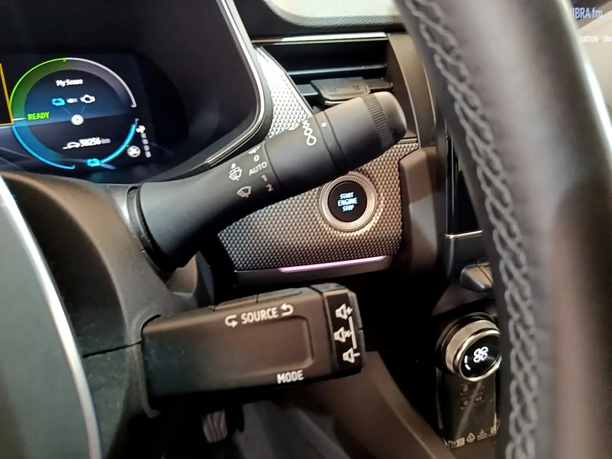 Gros plan intérieur sur le tableau de bord du Renault Arkana bleu, avec bouton démarrage et commandes au volant visibles.