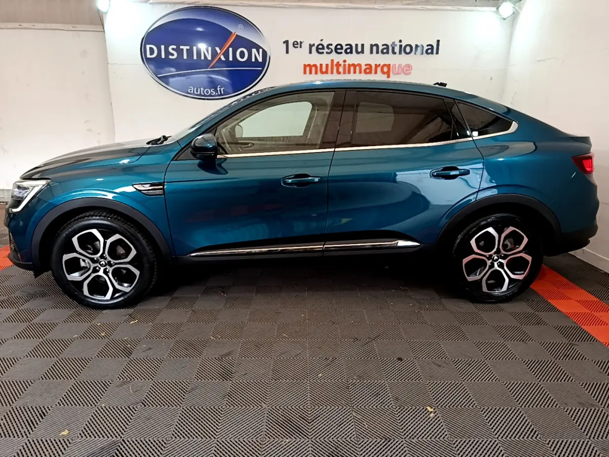 Renault Arkana bleu en profil droit, soulignant ses jantes alliage distinctives et sa silhouette coupé SUV.