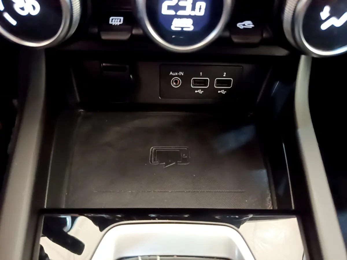 Gros plan sur la console centrale du Renault Arkana bleu, montrant les ports USB, prise Aux-IN et zone de recharge sans fil.