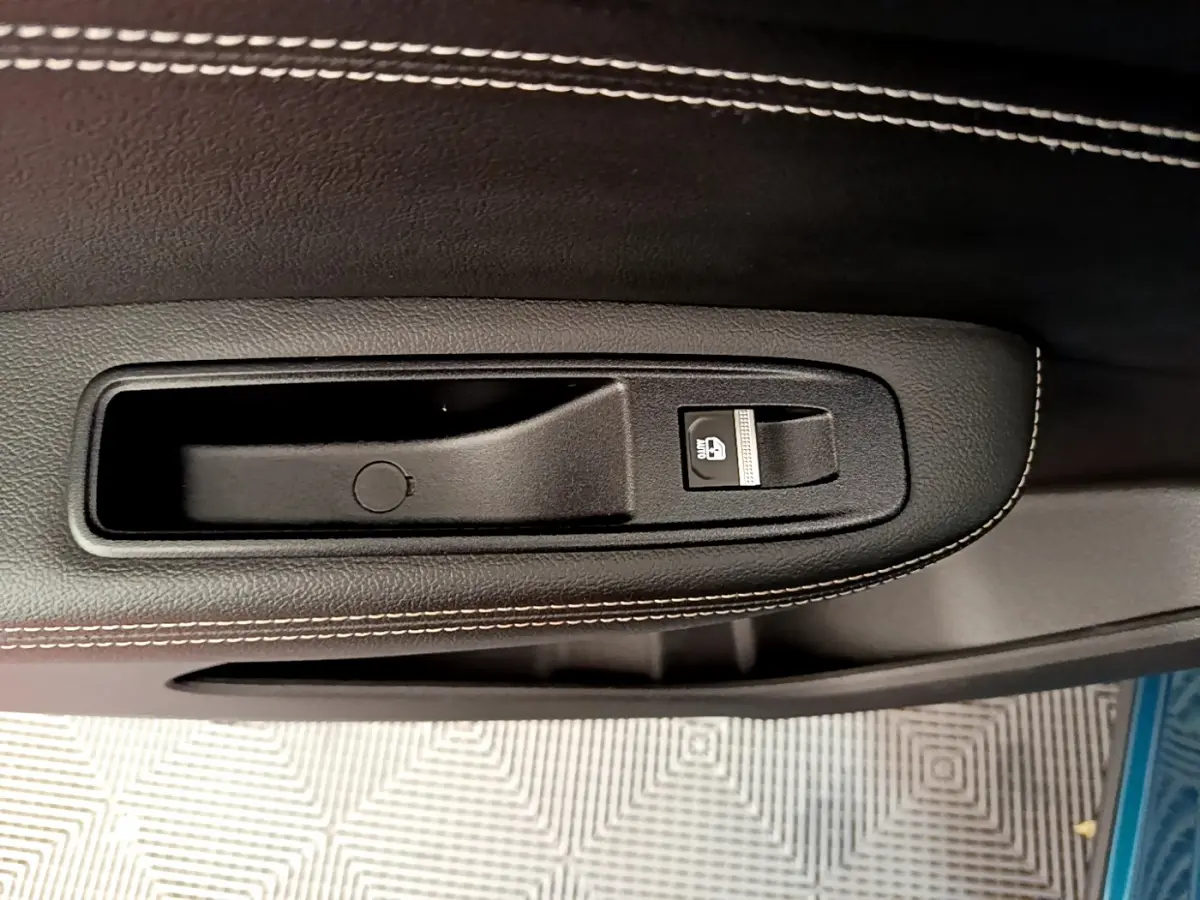 Gros plan sur la poignée intérieure noire avec bouton de verrouillage sur la porte d'une Renault Arkana Techno E-Tech bleu.