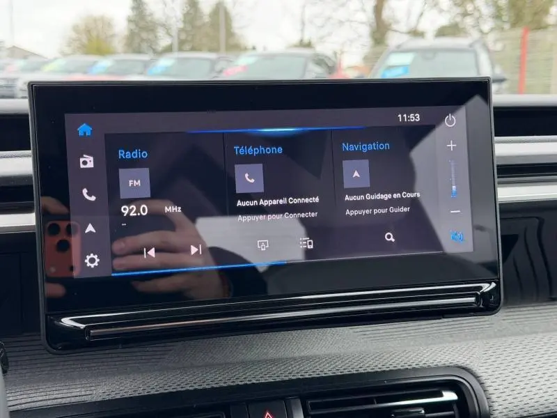 Écran tactile central de la Citroën C3 2025 affichant radio, téléphone et navigation, avec tableau de bord noir.