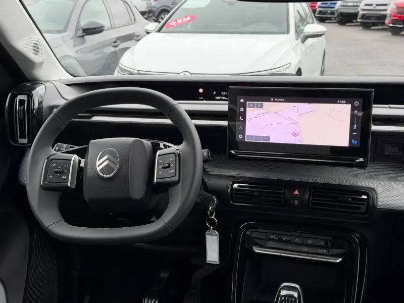 Vue intérieure du poste de conduite du Citroën C3 2025, avec volant multifonction et écran tactile de navigation.