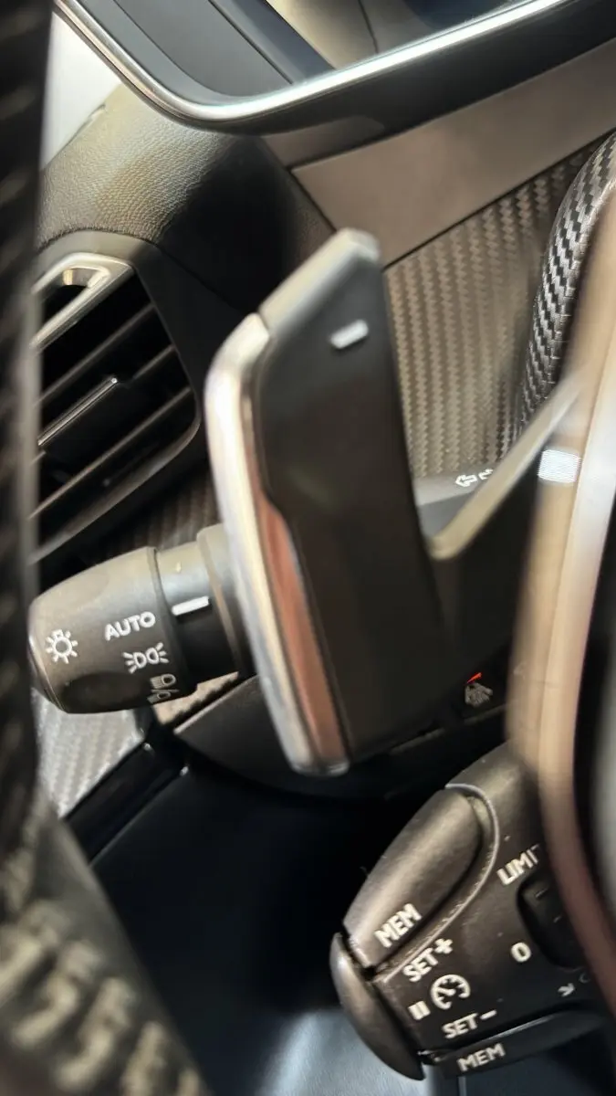 Détail intérieur côté gauche du Peugeot 2008 gris foncé, montrant commandes au volant et levier multifonctions.
