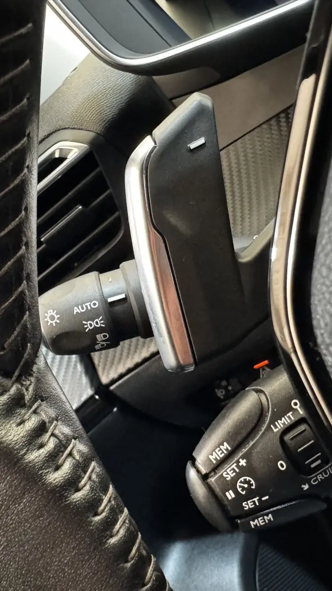 Gros plan sur les commandes au volant du Peugeot 2008 gris foncé, avec palettes de changement de vitesse et commandes de régulateur.