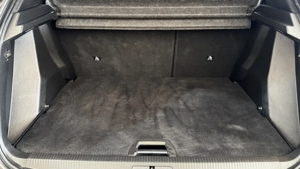Coffre ouvert du Peugeot 2008 gris foncé, vue de face montrant l'espace de chargement vide et tapis noir.
