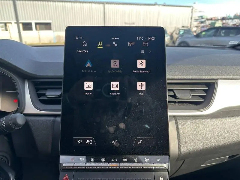 Écran tactile central du tableau de bord du Renault Captur 2025, affichant les options multimédia et climatisation.