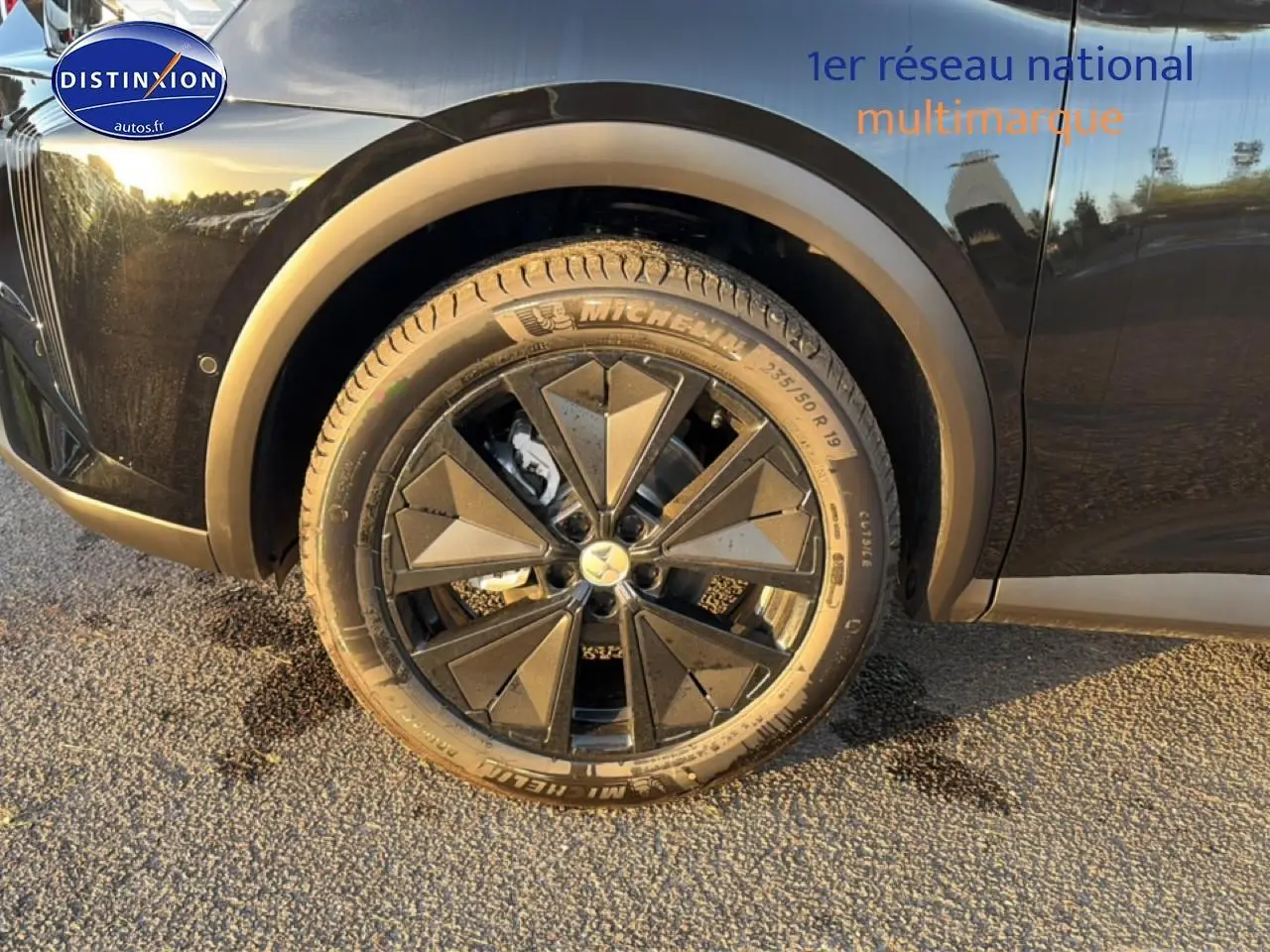 Gros plan sur la roue avant gauche noire du DS7 1.5 BlueHDi 130 Performance Line avec jante alu noire au soleil couchant.