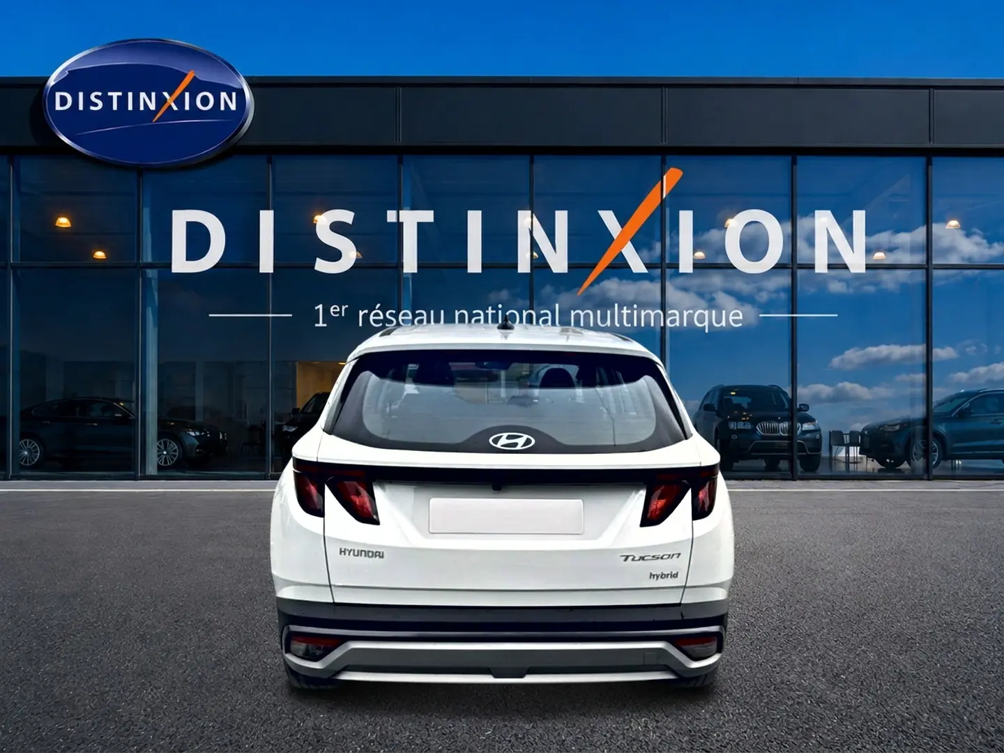 Vue arrière d'un Hyundai Tucson blanc hybride 2026, avec feux arrière sombres et logo Hyundai visible.