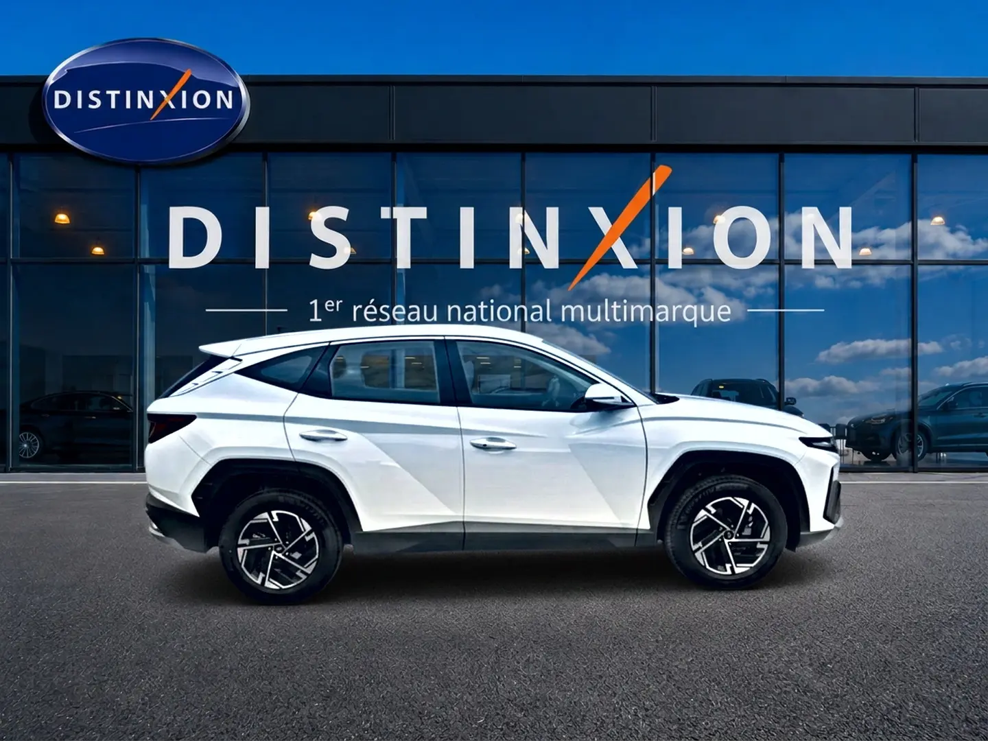 Profil droit d’un Hyundai Tucson blanc 2026 hybride, avec jantes alliage noires et toit noir contrasté.