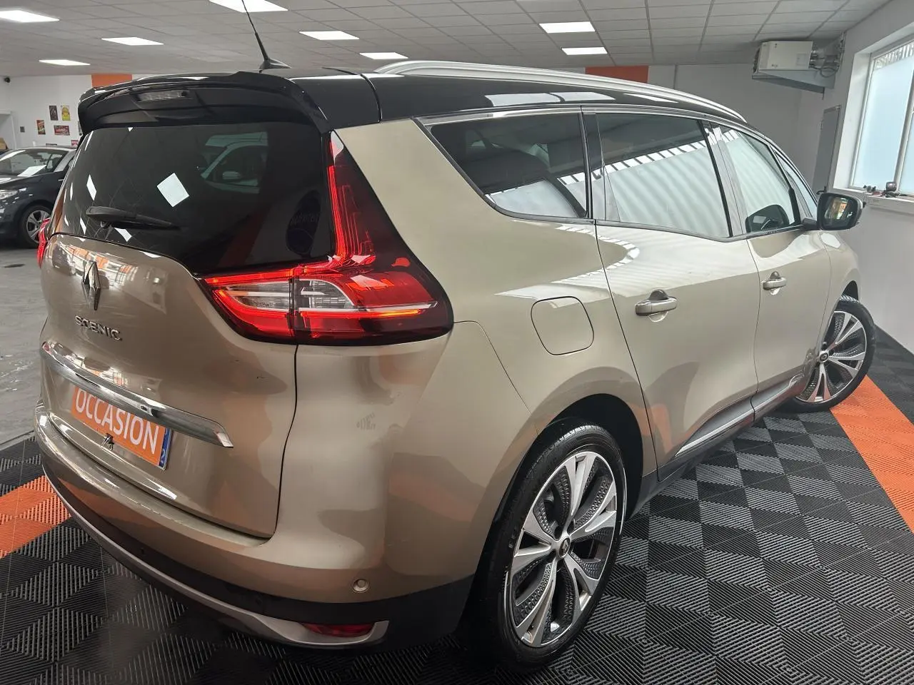 Vue 3/4 arrière droite d'un Renault Scénic Grand IV marron clair avec toit noir panoramique et jantes alliage 20 pouces.
