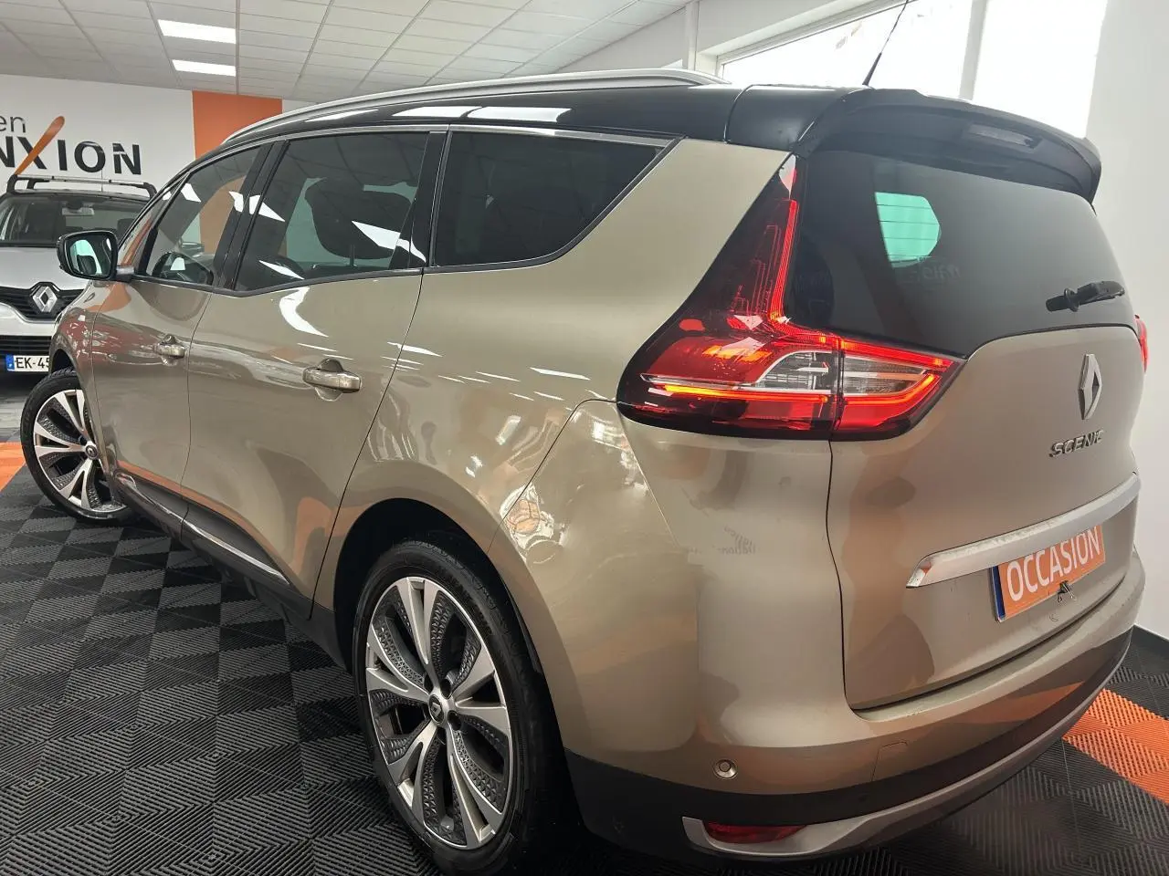 Vue 3/4 arrière droite d'un Renault Scénic Grand IV marron clair avec toit panoramique et jantes alliage 20 pouces.