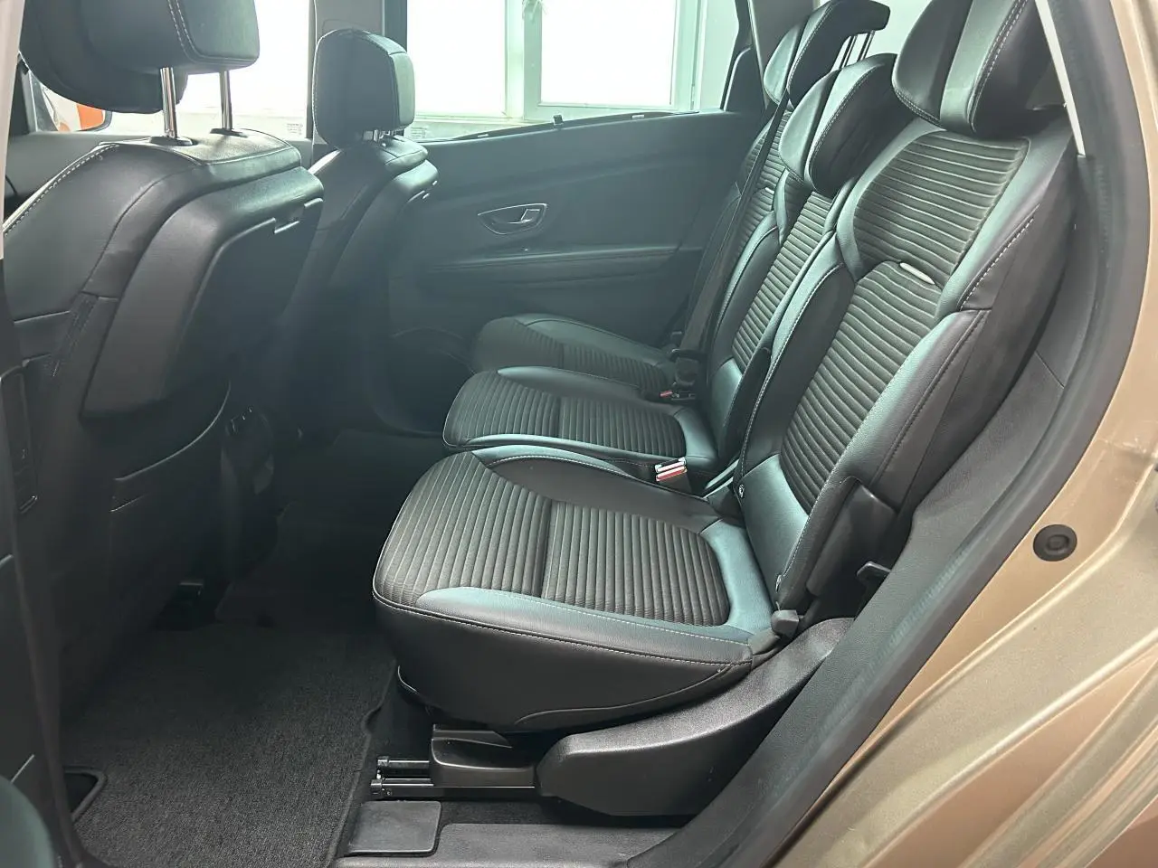 Vue latérale des sièges arrière en cuir noir du Renault Scenic Grand IV marron clair, avec appuie-têtes et ceintures visibles.