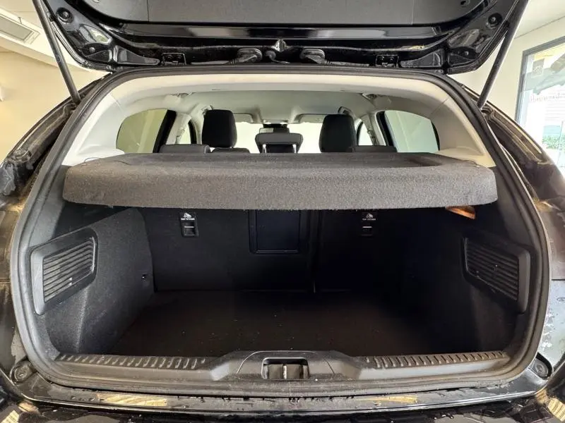 Coffre ouvert vu de l'arrière d'une Ford Focus noir Agate métallisé avec cache-bagages et sièges arrière visibles.