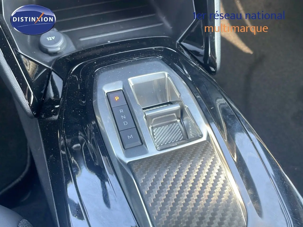 Gros plan sur la console centrale du Peugeot 2008 Hybrid 136ch avec levier de vitesses automatique et finition carbone.