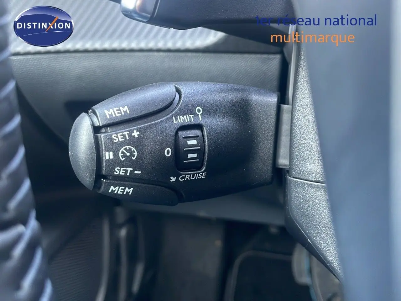 Gros plan sur la commande de régulateur de vitesse du Peugeot 2008 Hybrid gris Artense, côté gauche du volant.