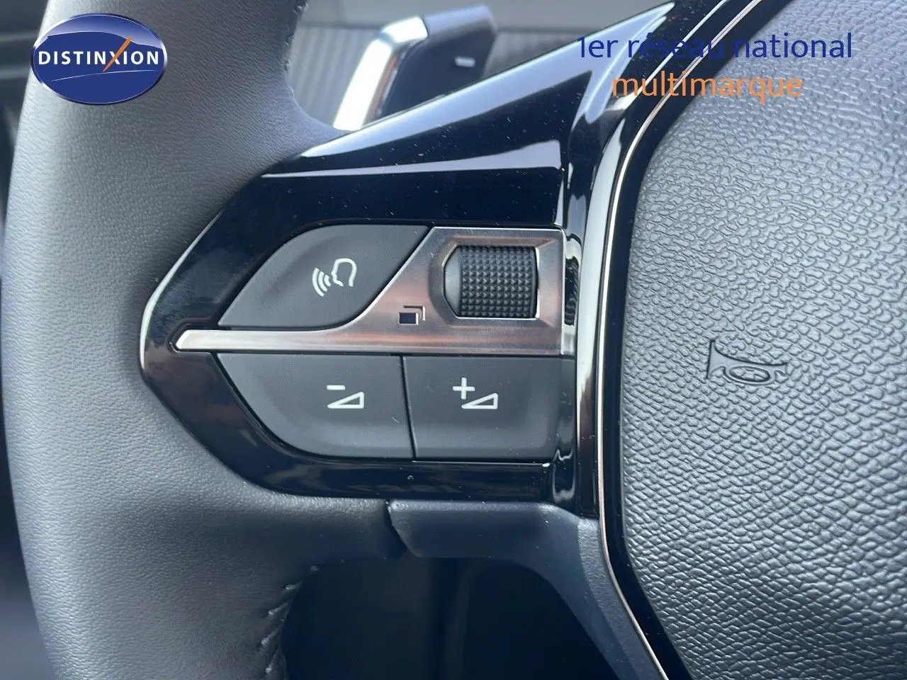 Gros plan sur les commandes de volume et appel au volant noir du Peugeot 2008 Hybrid gris Artense 2025.
