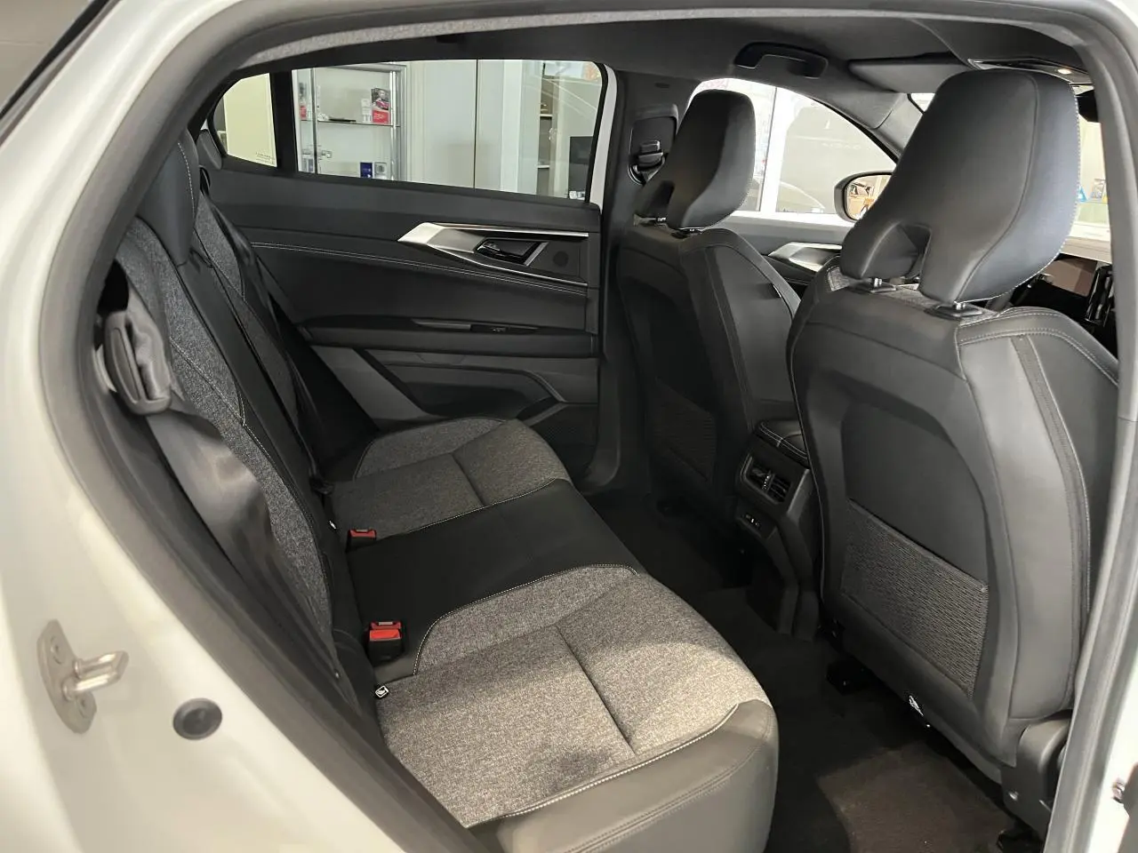 Vue intérieure côté gauche des sièges arrière gris clair et noir du Renault Rafale blanc 2025 avec finitions textiles et cuir.