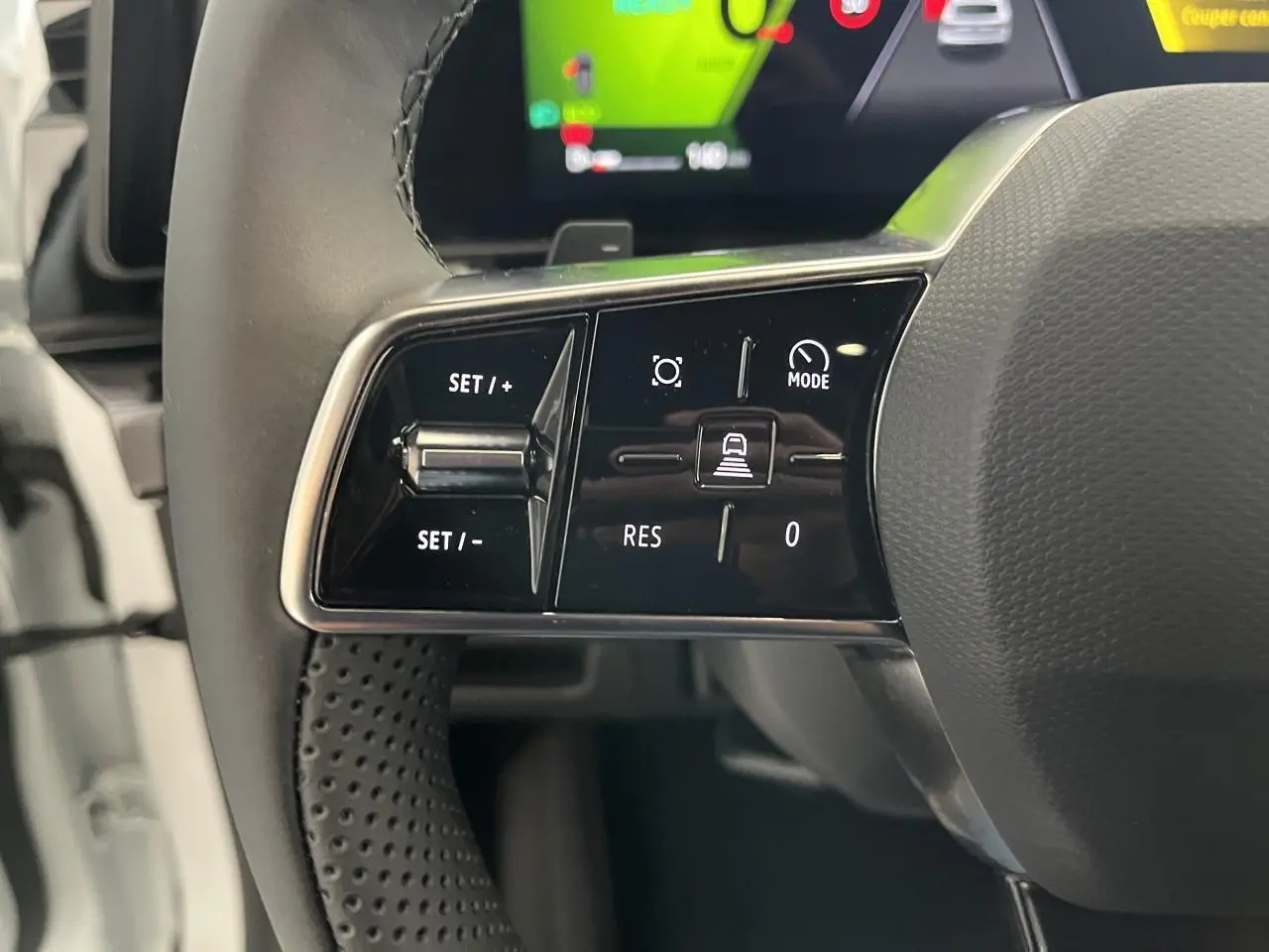 Gros plan sur les commandes à gauche du volant textile refined d'une Renault Rafale blanche, affichage numérique en arrière-plan.