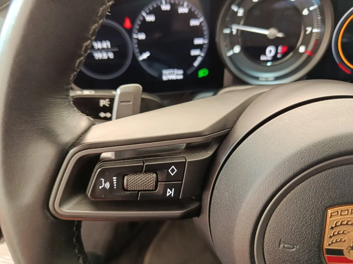 Gros plan sur le volant cuir noir d’une Porsche 911 Carrera 4S 2019 avec commandes multifonctions et tableau de bord numérique.