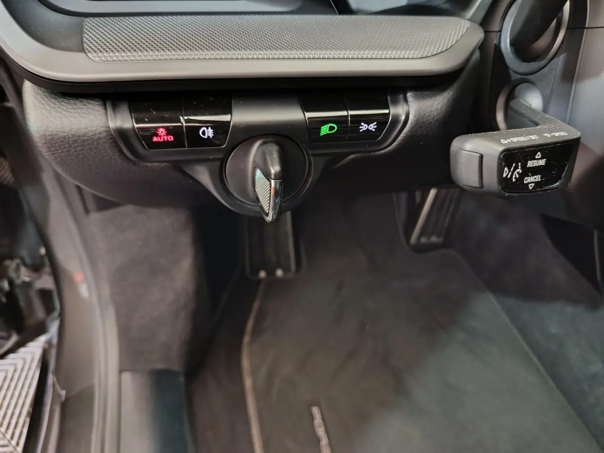 Gros plan sur les commandes d’éclairage et le levier de régulateur de vitesse dans l’habitacle noir d’une Porsche 911 Carrera 4S Coupé 2019.