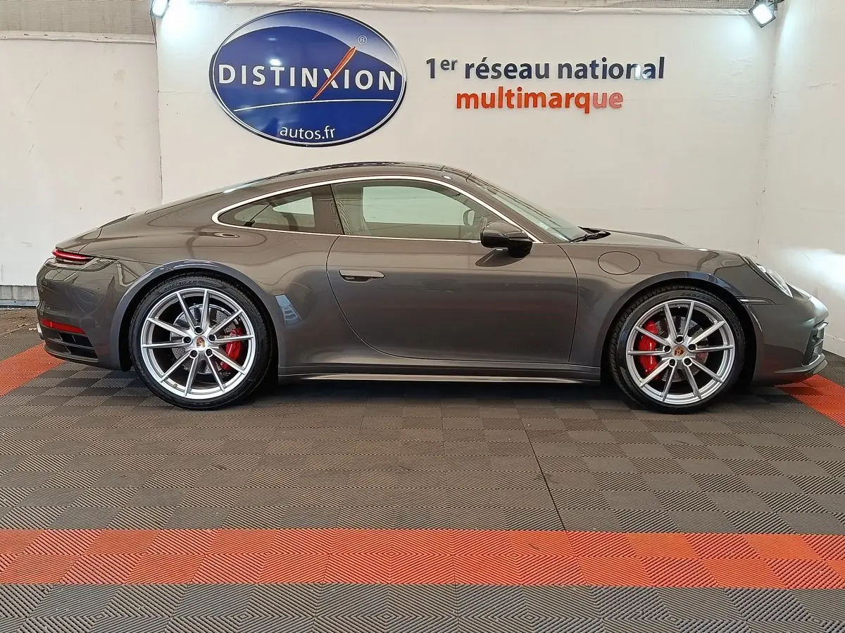 Vue de profil côté gauche d'une Porsche 911 Carrera 4S Coupé gris foncé avec jantes sport et étriers rouges.